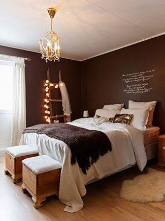 a bed room with a neatly made bed next to a window and a chandelier