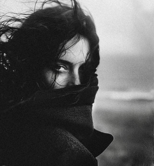 a black and white photo of a woman with her hair blowing in the wind