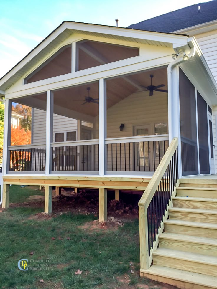 a screened porch with stairs leading up to the front door and second story deck area