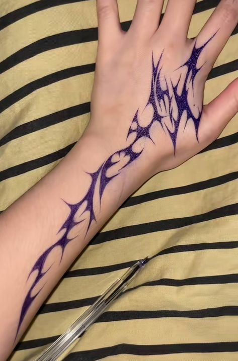 a person's hand with tattoos on it and scissors in front of the arm