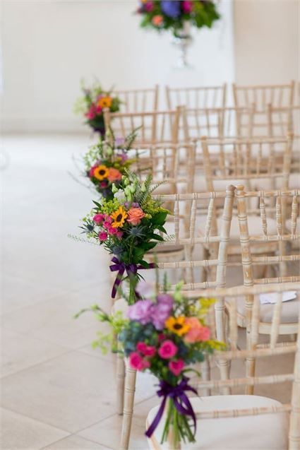 rows of chairs with flowers on them in a room filled with white tile flooring