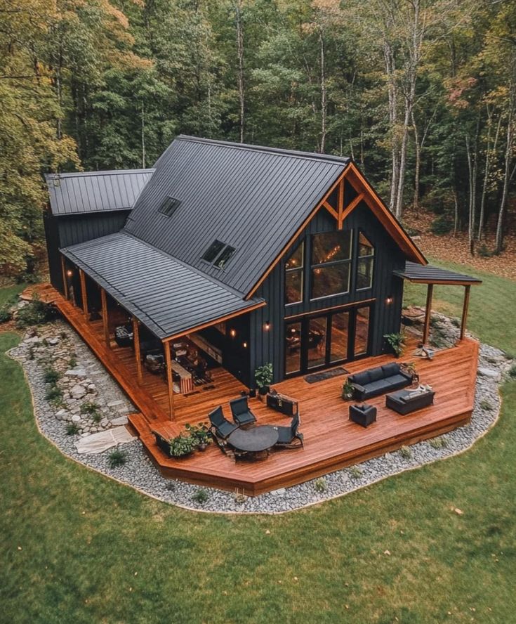 an aerial view of a house in the middle of a wooded area with patio furniture