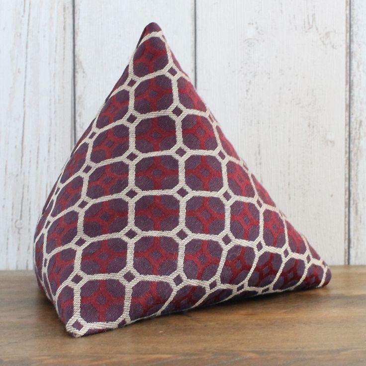 a red and white triangle shaped pillow sitting on top of a wooden table