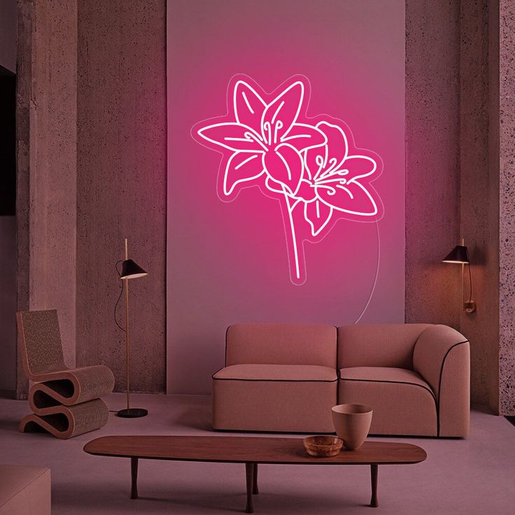 a living room with a couch, coffee table and pink neon flower on the wall