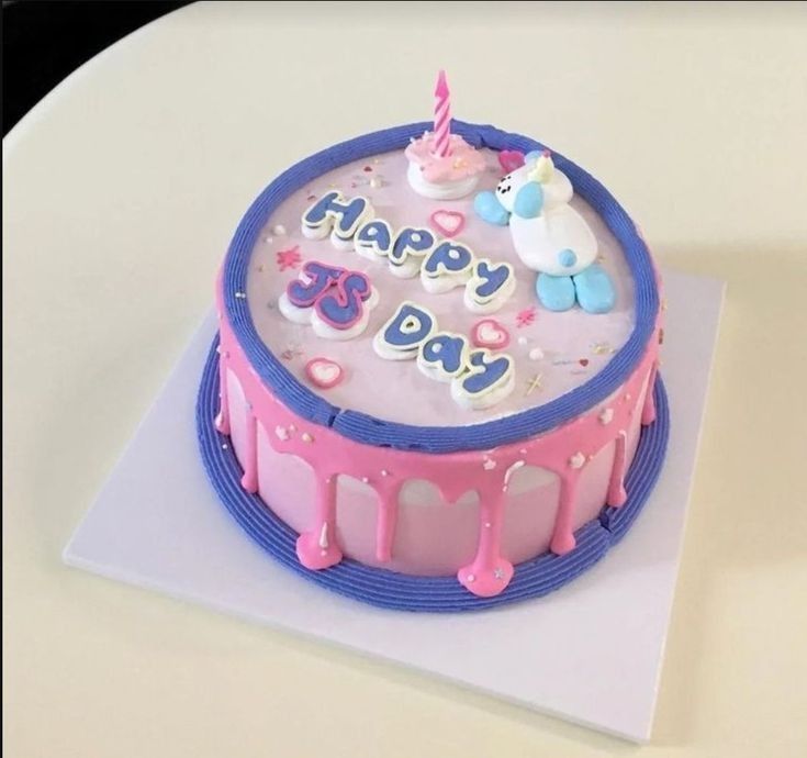 a birthday cake with pink icing and decorations on it, sitting on top of a white table