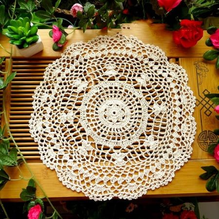 a white doily sitting on top of a wooden table surrounded by flowers and greenery