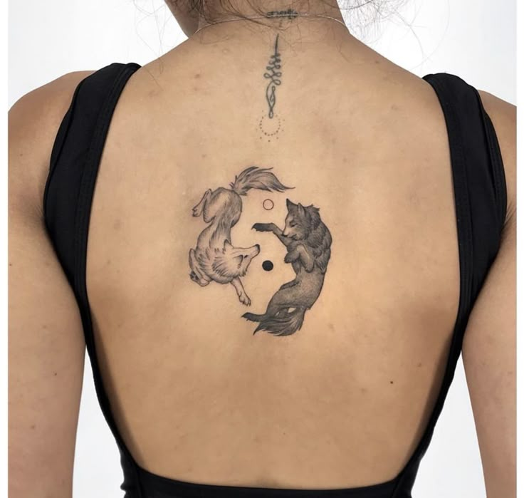 the back of a woman's neck with a tattoo of two fish on it