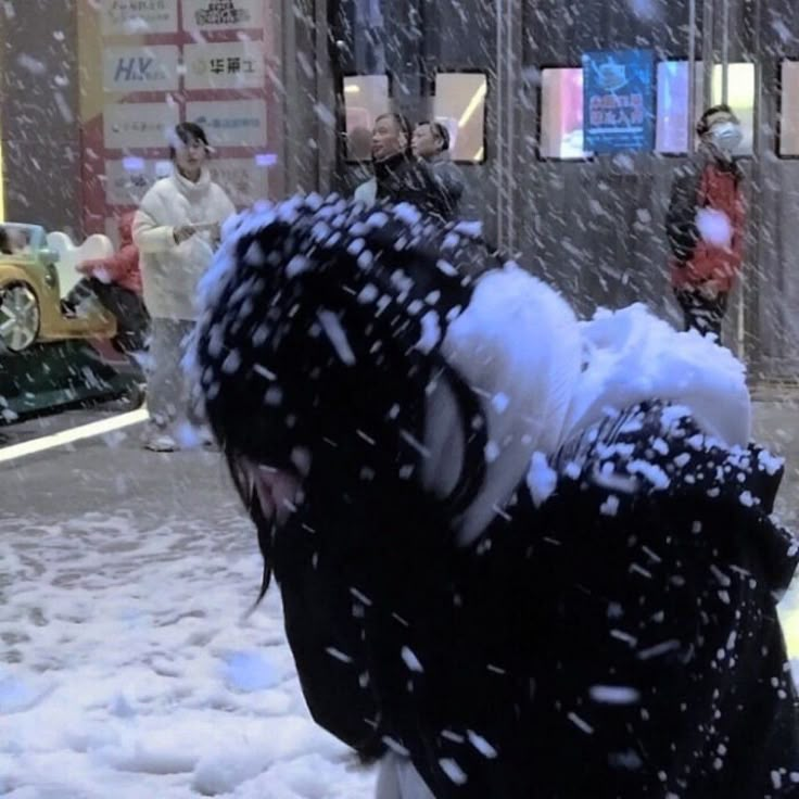 a person is walking in the snow with an umbrella on their head and other people behind him