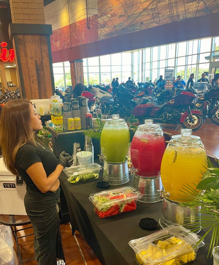 a woman standing in front of a table filled with drinks