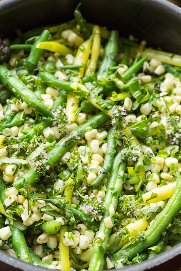 broccoli, corn and green beans are mixed together in a skillet on the table