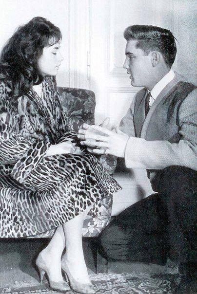 a man in a suit and tie sitting next to a woman who is holding something