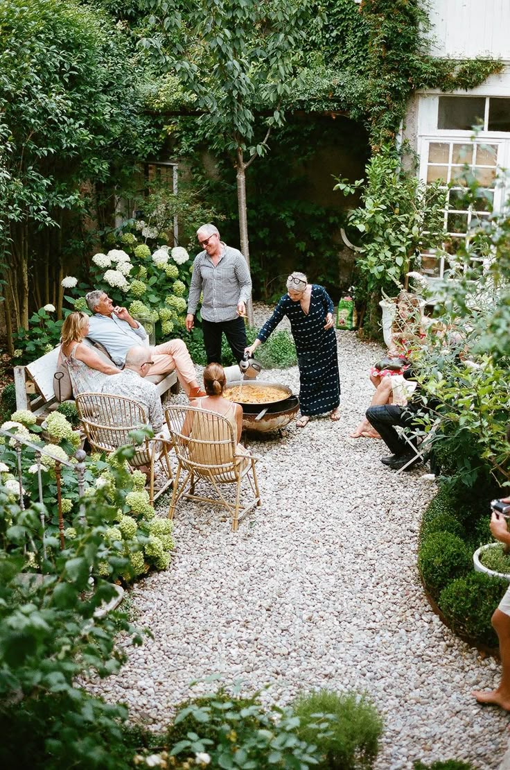 a group of people sitting around a table in a garden