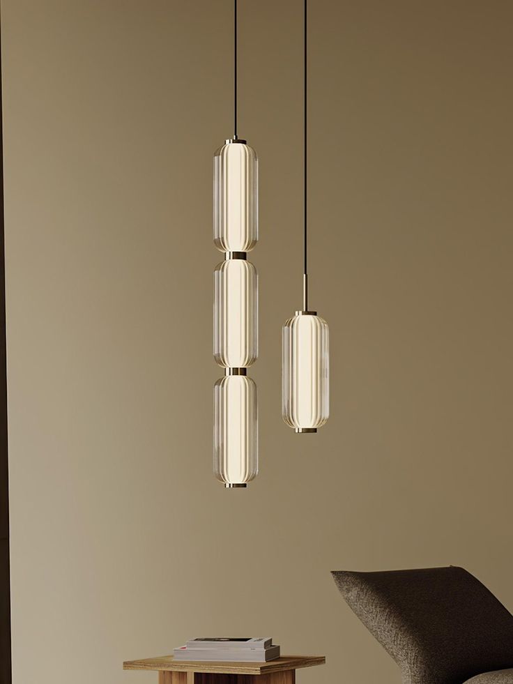 three light fixtures hanging from the ceiling in a room with a chair and table next to it