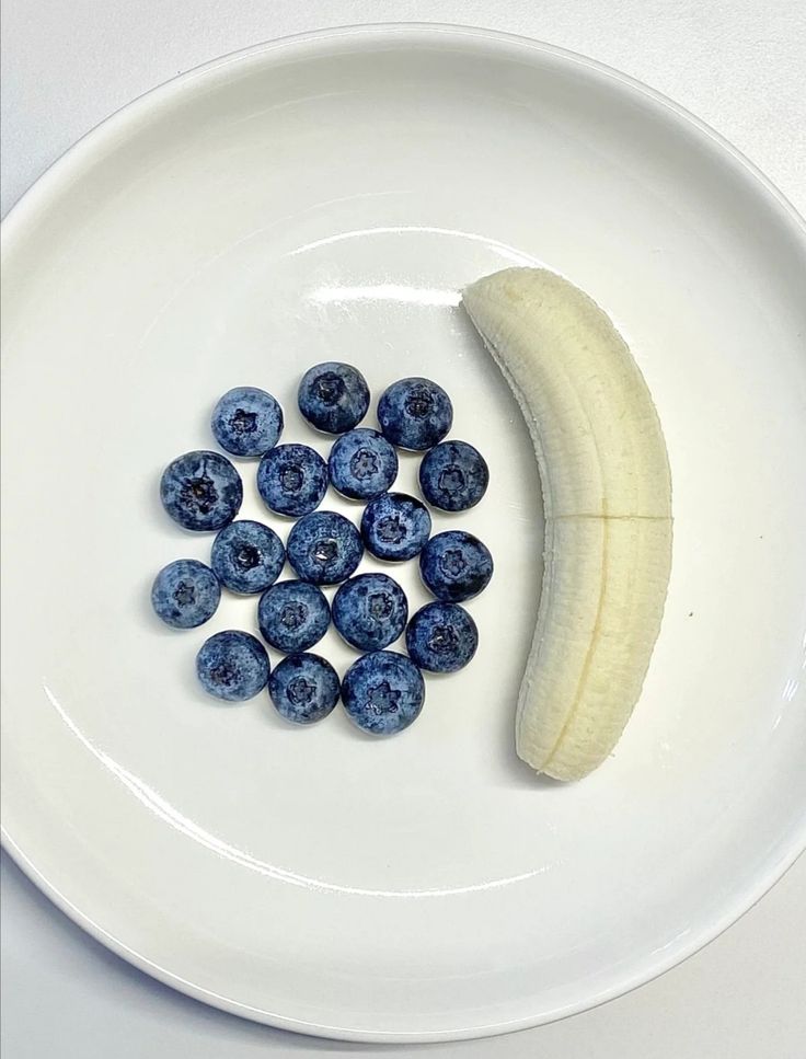 a banana and some blueberries on a white plate