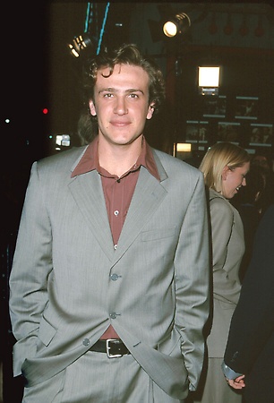 a man in a gray suit and red shirt