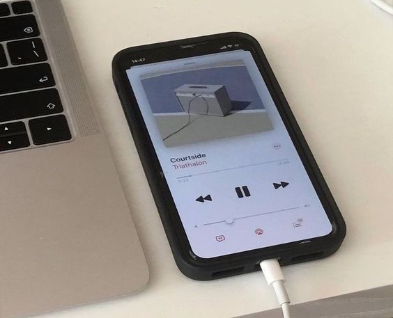 an iphone is plugged into a charger on a desk next to a laptop