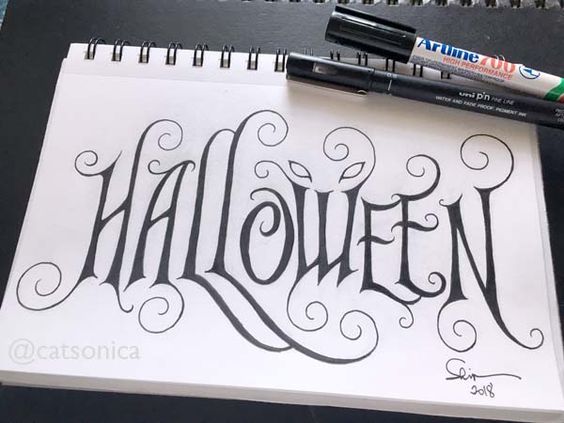 the word halloween written in cursive writing on a notepad next to markers