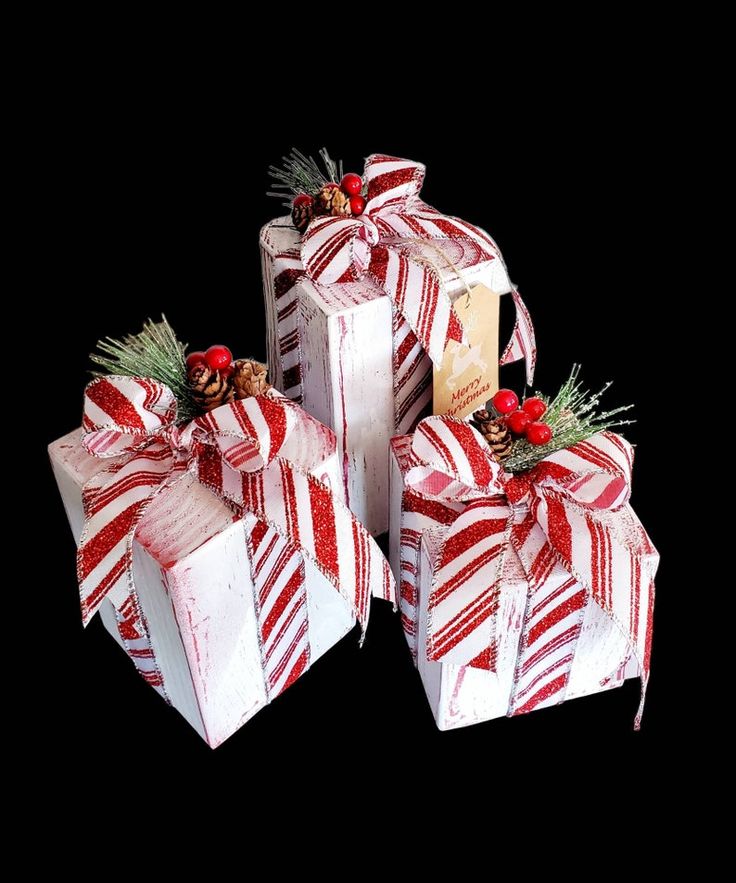 three wrapped christmas presents sitting next to each other on a black surface with red and white stripes