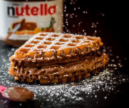 two waffles with chocolate frosting and nutella spread on them next to a can of nutella