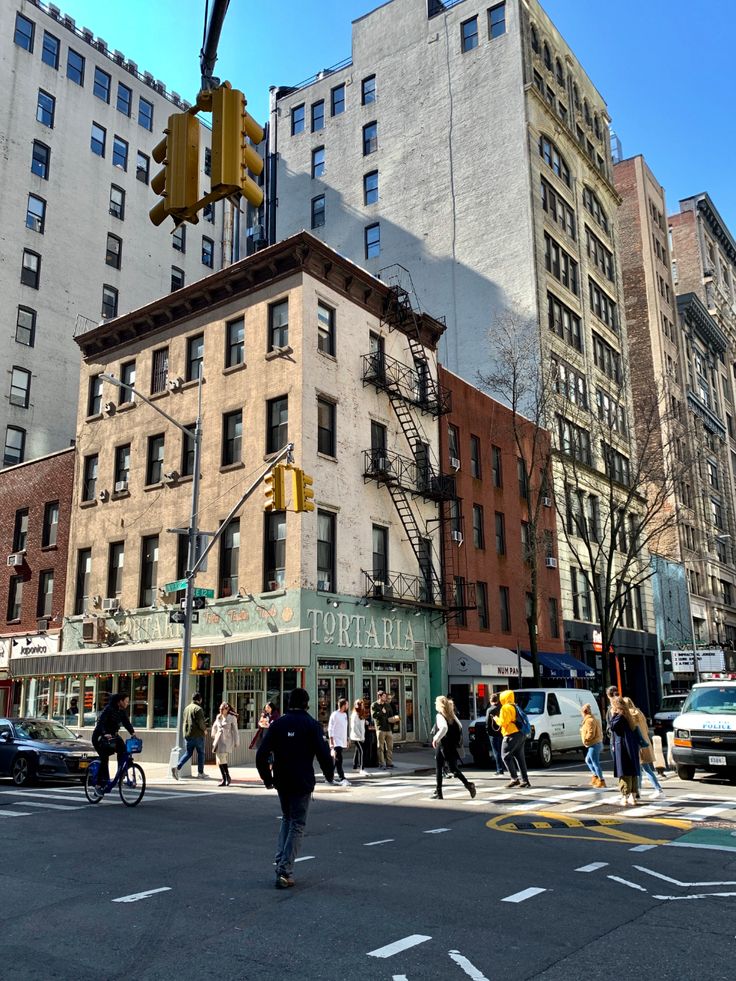 people crossing the street in front of tall buildings