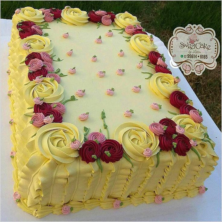 a large yellow cake with red and pink flowers on it's side sitting on a table