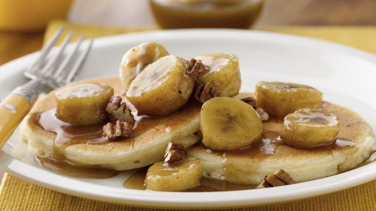 bananas and pecans are on top of pancakes with caramel syrup in the background