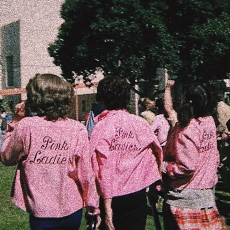 three girls in pink shirts are walking down the street