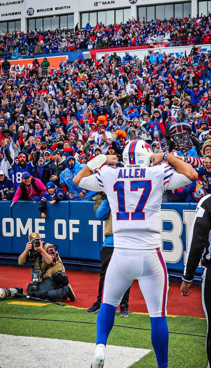 a football player standing on top of a field with his arms up in the air