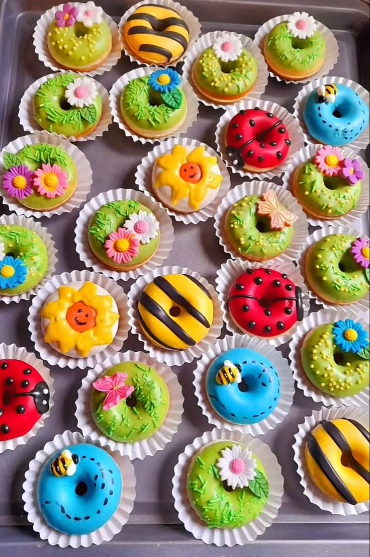 there are many cupcakes in the tray with different designs on them, including ladybugs and bees