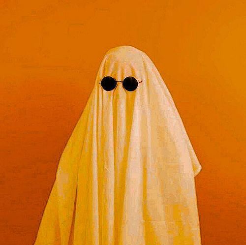 a yellow ghost with black sunglasses on it's face and eyes are standing in front of an orange wall