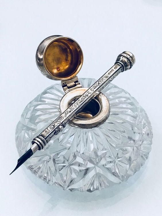 a fountain pen sitting on top of a crystal bowl with a ball in the middle