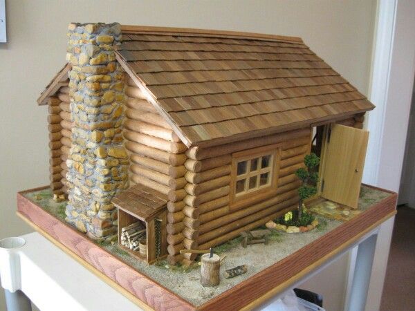 a model log cabin on top of a table in front of a door and window