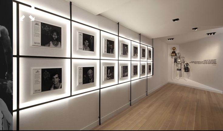 an empty room with many framed photographs on the wall and wood flooring in front of it