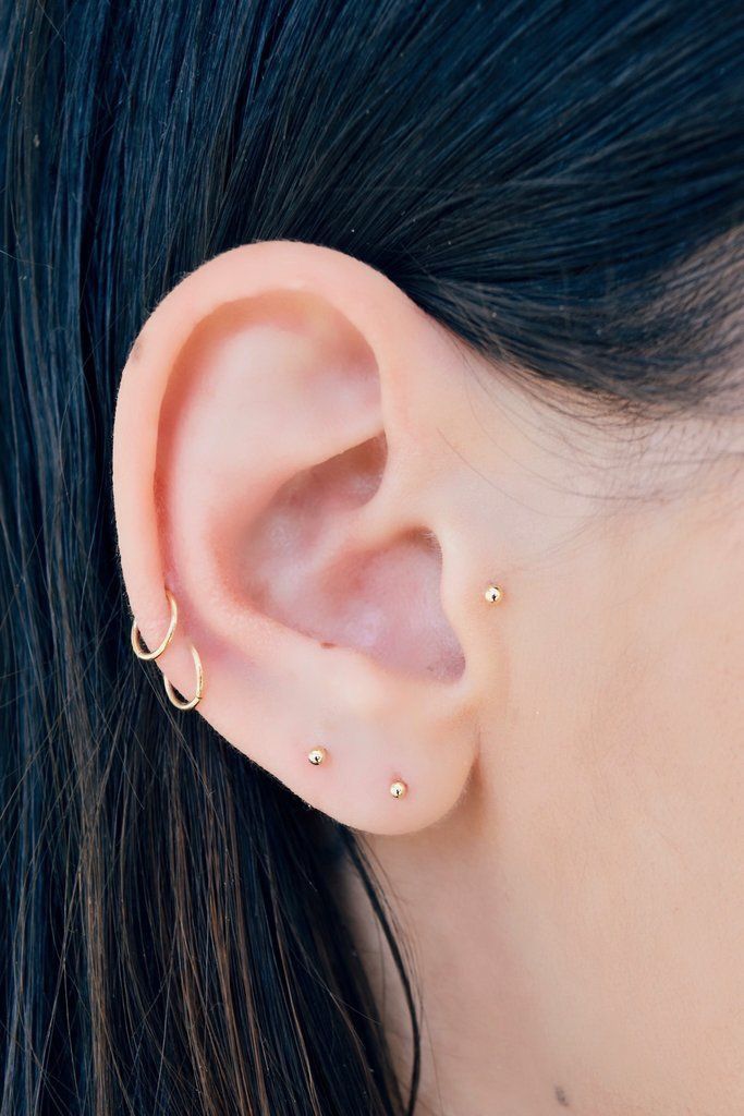 a close up of a person wearing an ear with two small gold rings on it