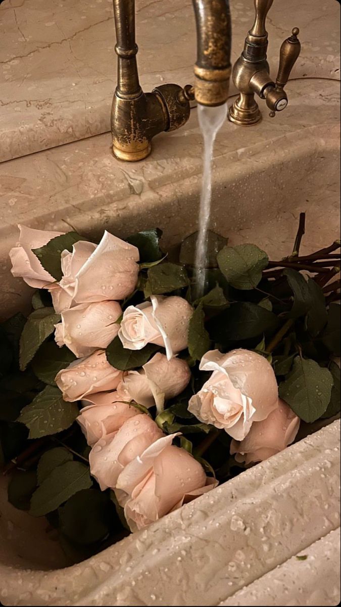 a bunch of pink roses sitting in a sink with water coming out of the faucet