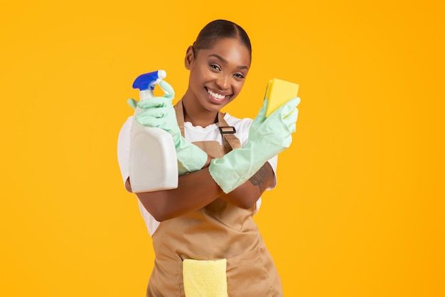 a woman in an apron and rubber gloves is holding a cleaning product