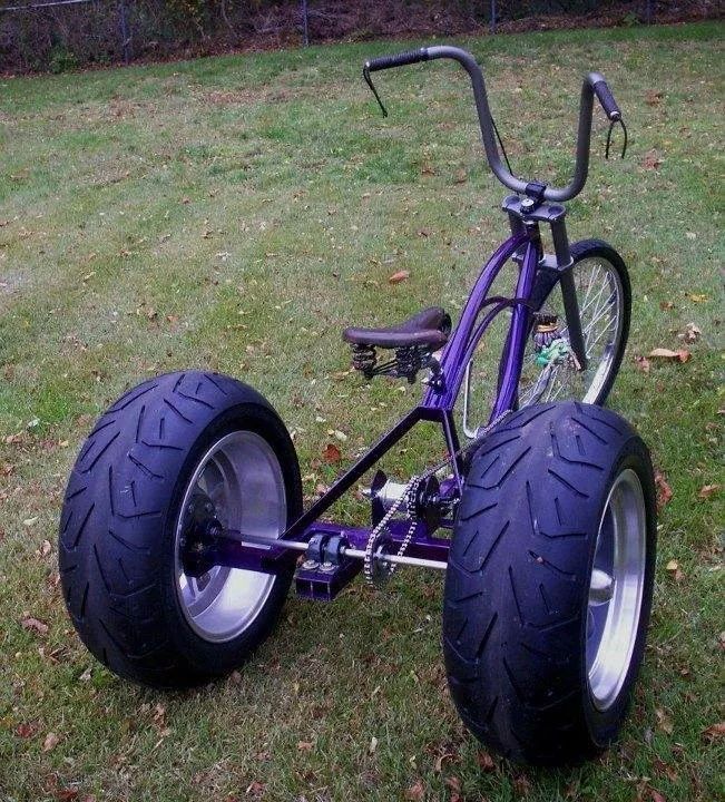 a purple bike with big tires parked in the grass