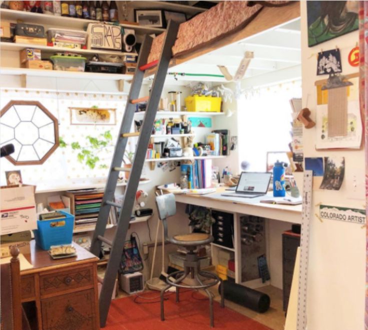 a room with a ladder that is next to a desk