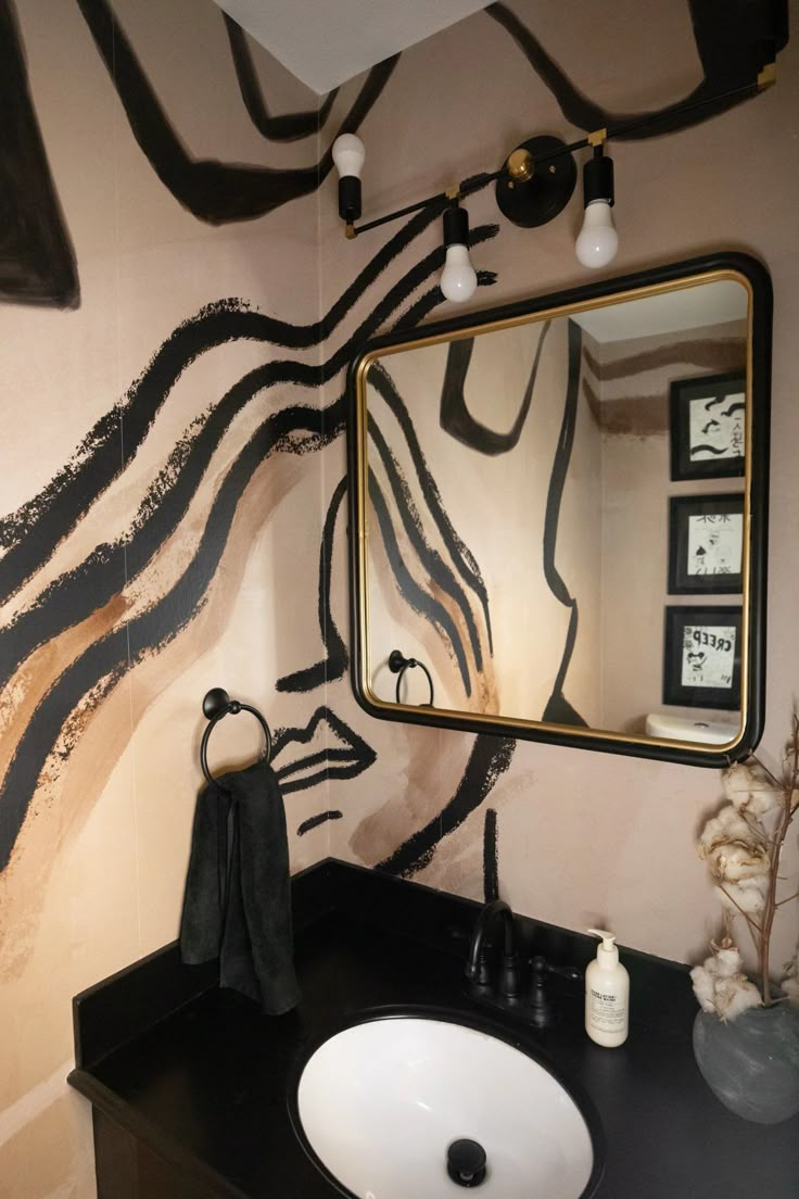 a bathroom with a sink, mirror and artwork on the wall