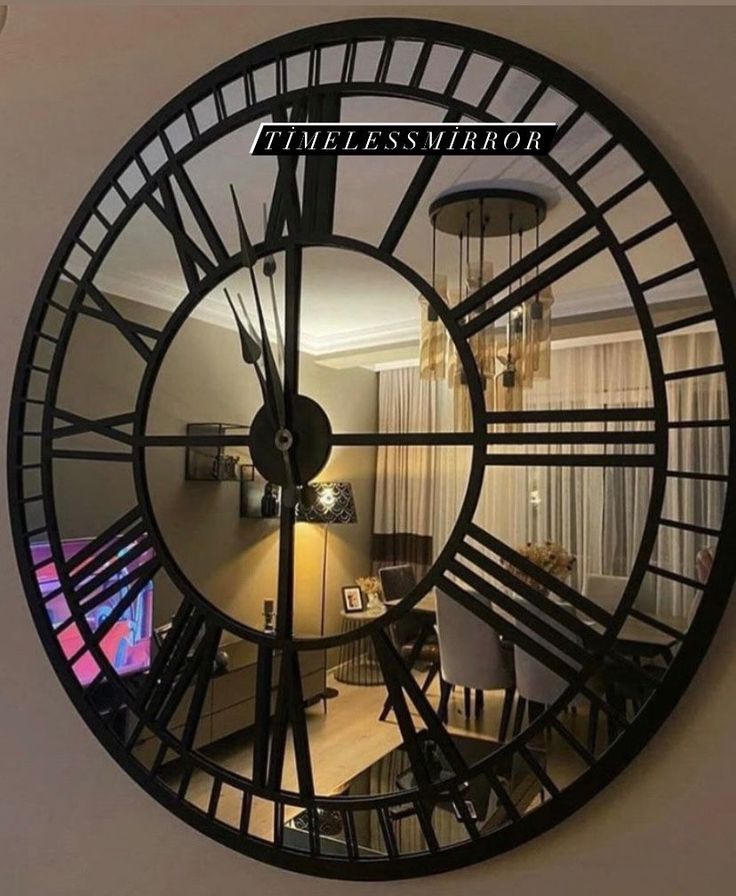 a large black clock hanging from the side of a wall next to a living room