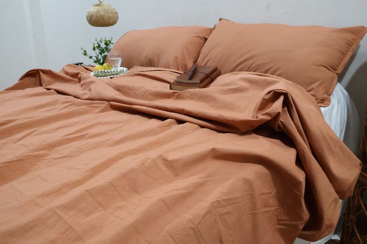 an unmade bed with brown sheets and pillows