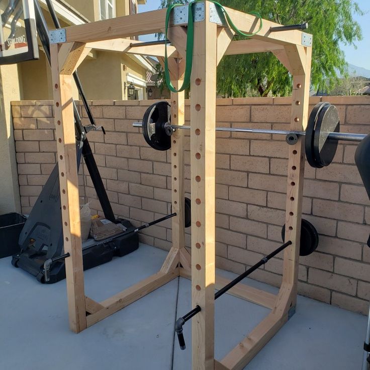 a home gym set up in front of a brick wall with bars and weight machines