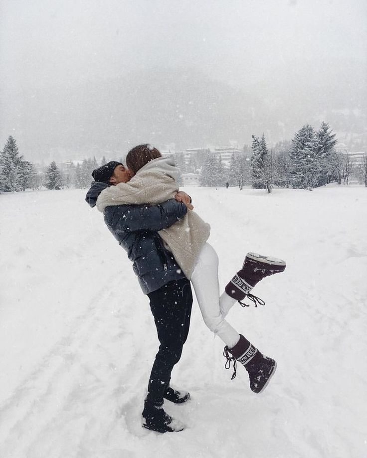 a man and woman are kissing in the snow with their feet on each other's shoulders