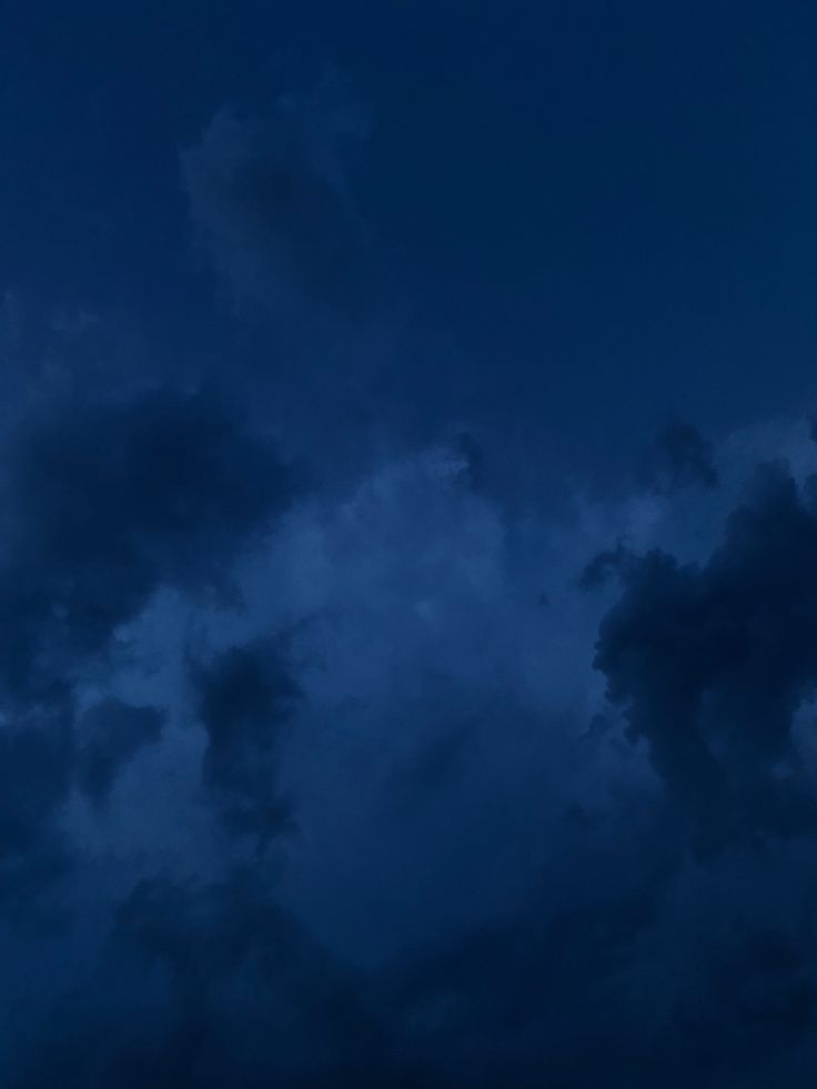 the airplane is flying high in the sky at night, with dark clouds behind it