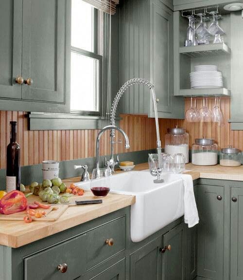 a kitchen filled with lots of green cabinets and counter top space next to a white sink