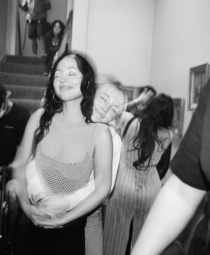 black and white photograph of woman in mesh top with other women around her looking at the camera