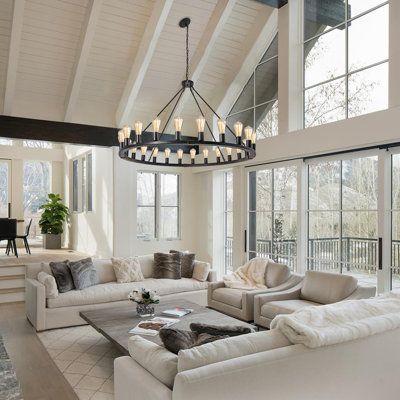 a living room filled with lots of furniture and a chandelier hanging from the ceiling