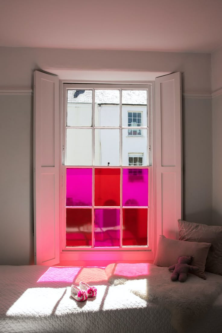 a bedroom with pink and red squares on the window sill in front of it