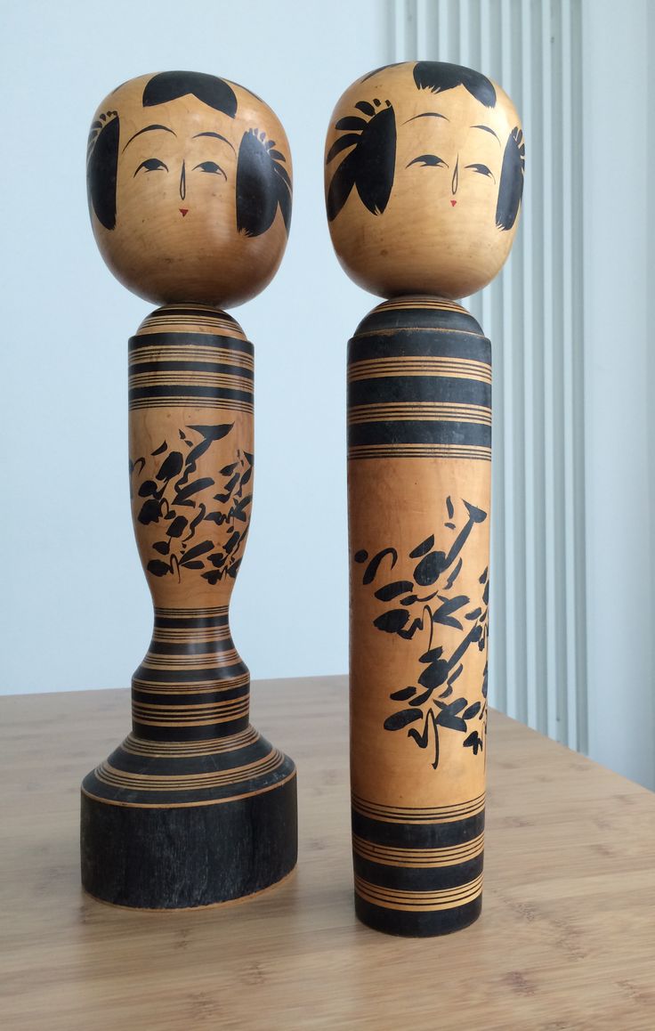 two wooden dolls sitting next to each other on a table