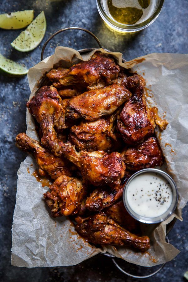 chicken wings with dipping sauce and lemon wedges next to it on a blue surface